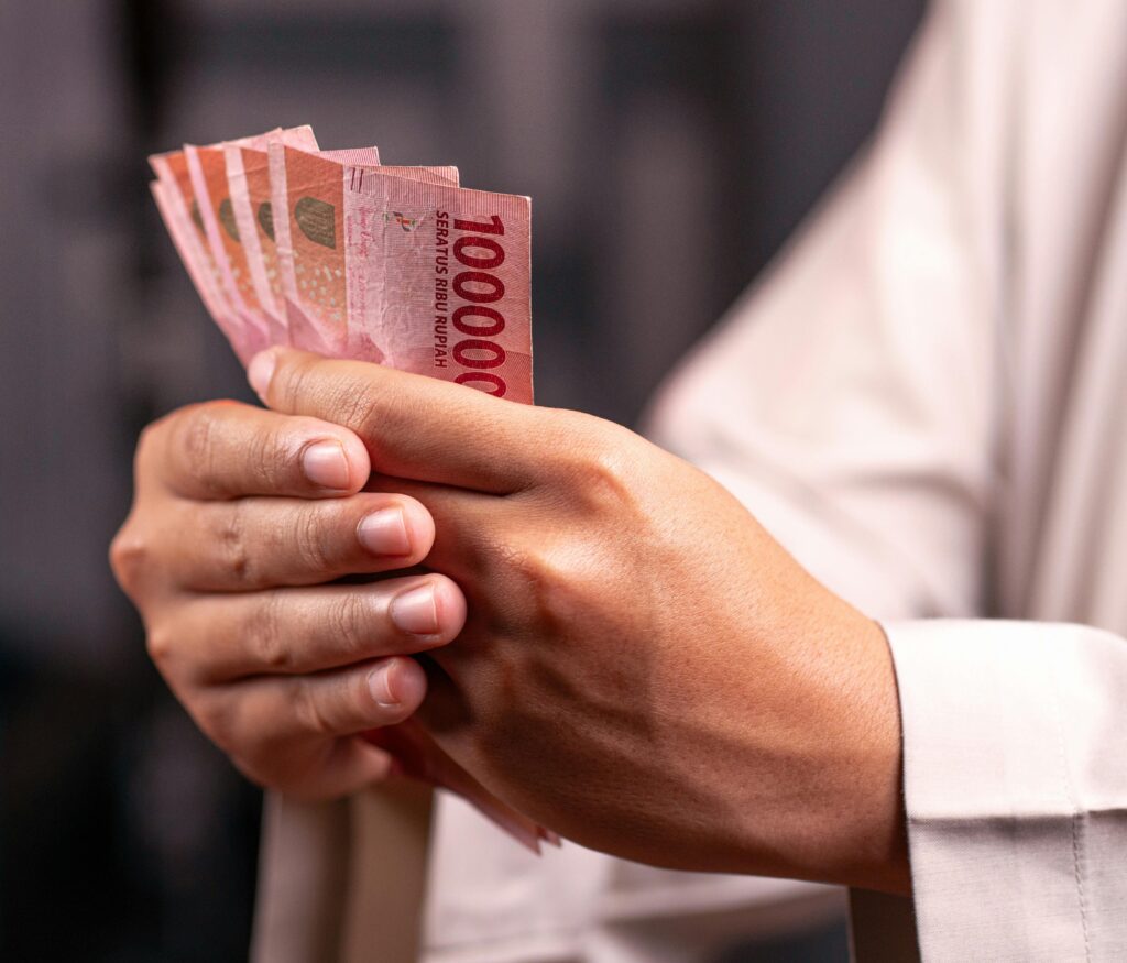 Home Close-up of hands holding Indonesian Rupiah 100,000 bills, highlighting financial and economic concepts.