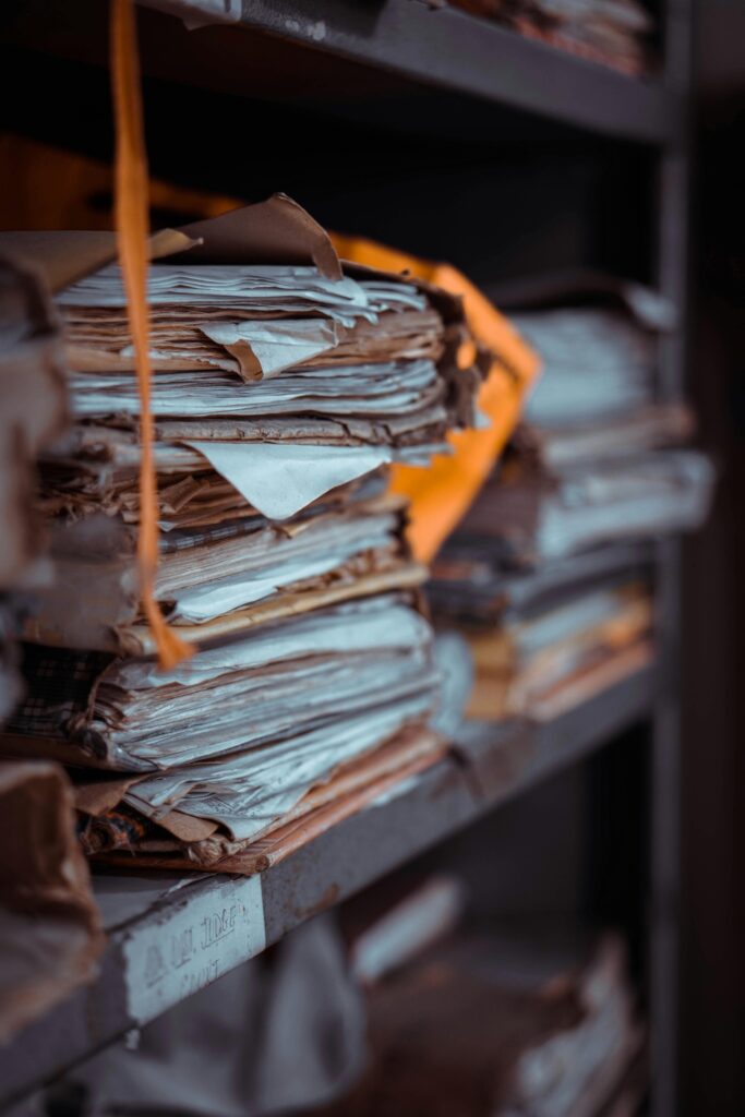 Home Stacks of old documents and papers piled on dusty shelves, creating an organized yet chaotic scene.
